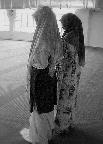 Gambar hitam putih dua wanita bertelekung berdiri bersolat di dalam surau