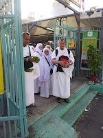 Jemaah berihram berdiri di pintu masuk kawasan khemah maktab di Arafah