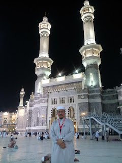 Dr. Abu Anas Madani berdiri di hadapan menara Masjidil Haram pada waktu malam