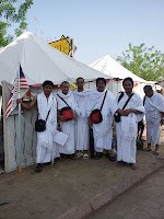 Jemaah lelaki berihram bergambar di hadapan khemah di Arafah